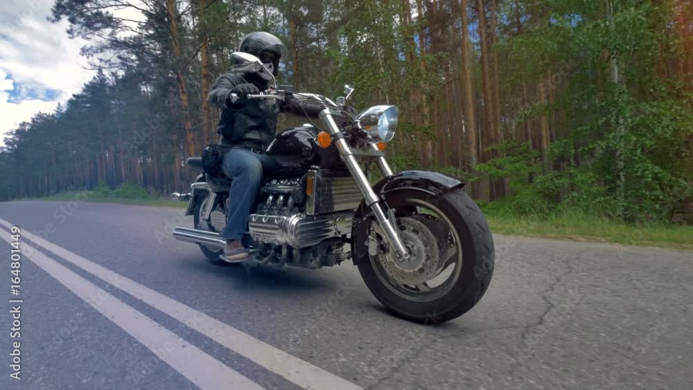 A biker riding a motorcycle wearing black clothes and helmet. A biker riding a motorcycle wearing black clothes and helmet.