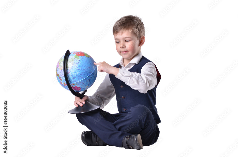 Sitting schoolboy pointing on a globe of world