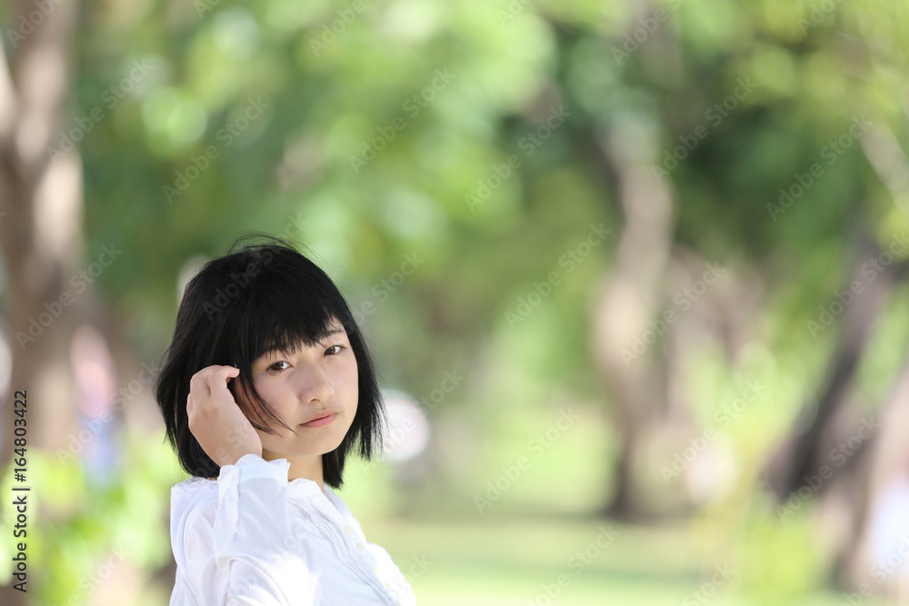 Asian young woman thinking and looking portrait with green tree background Asian young woman thinking and looking portrait with green tree background