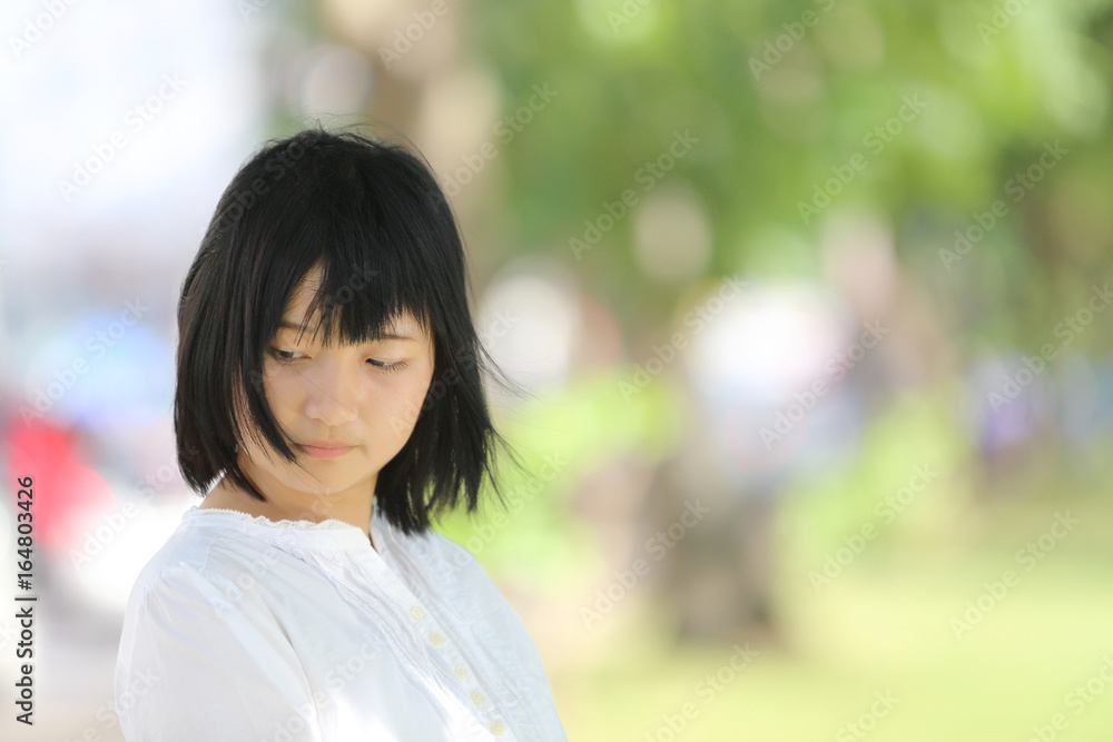 Asian young woman thinking and looking portrait with green tree background Asian young woman thinking and looking portrait with green tree background