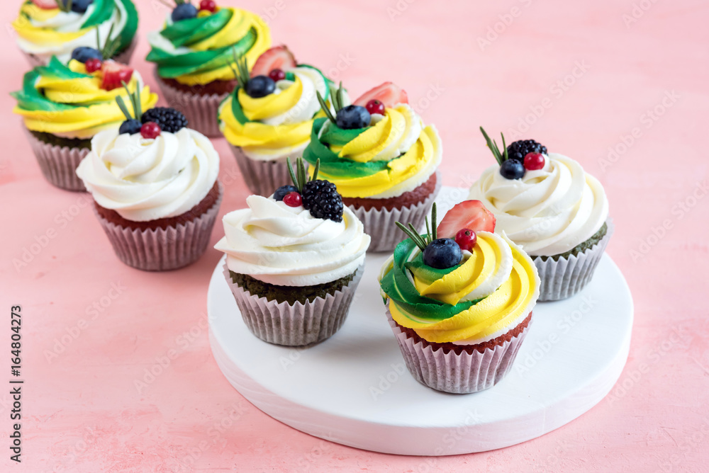 Tasty cupcakes with cream cheese topped with fresh berries Pink background Beautiful cupcakes decorated with colorfull cream cheese Tasty cupcakes with cream cheese topped with fresh berries Pink background Beautiful cupcakes decorated with colorfull cream cheese