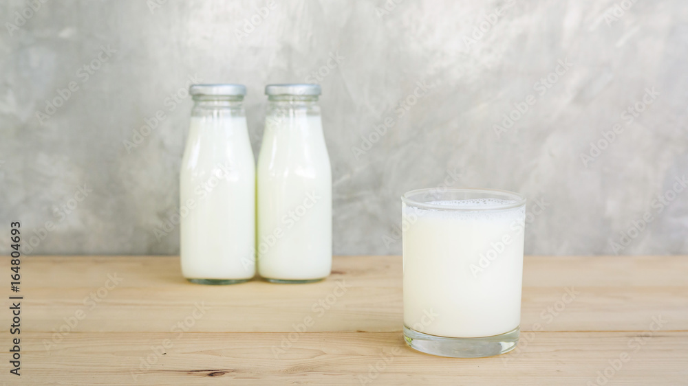 a bottle and glass of milk on a wooden table. a bottle and glass of milk on a wooden table.