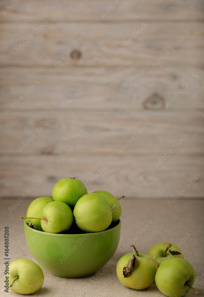 Green apples in a green plate on a wooden light background. Green apples in a green plate on a wooden light background.