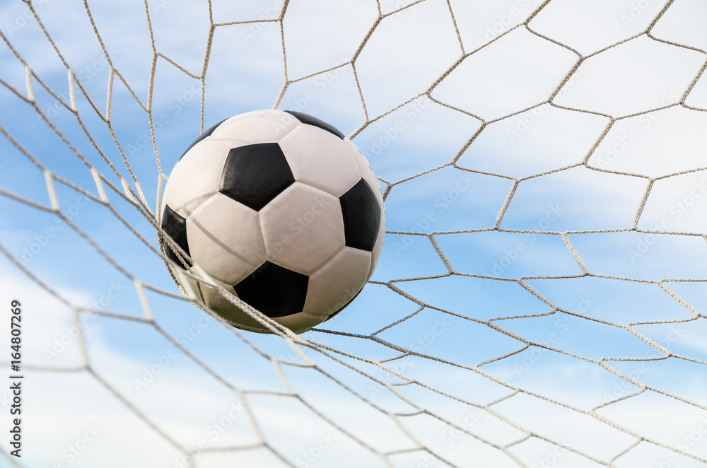 Naklejka premium Soccer football in Goal net with the sky field.
