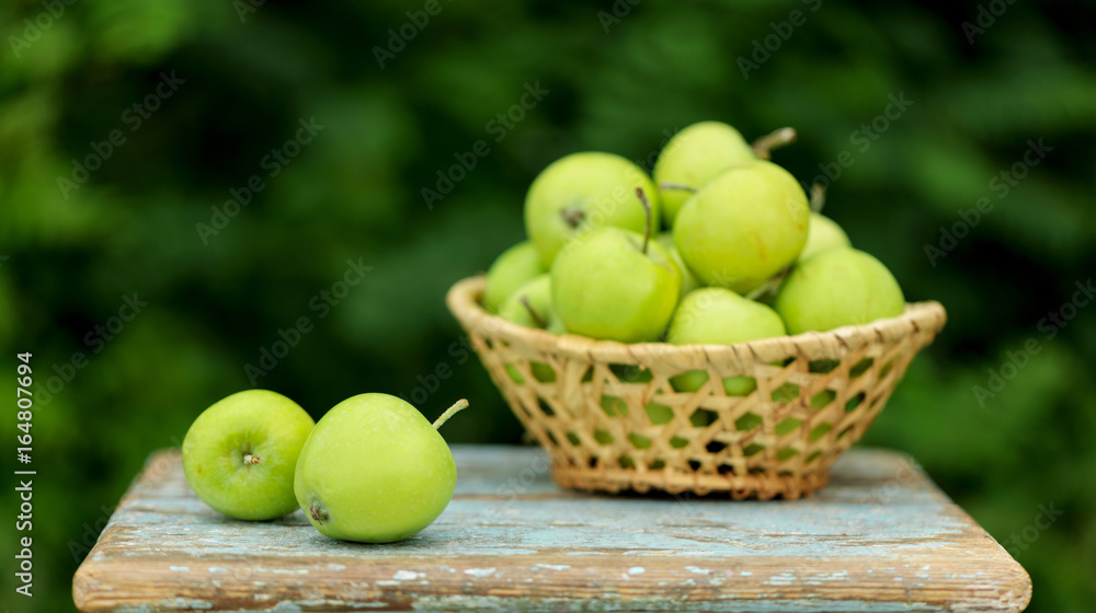 Homemade rustic green apples in a basket on an old stool. Homemade rustic green apples in a basket on an old stool.