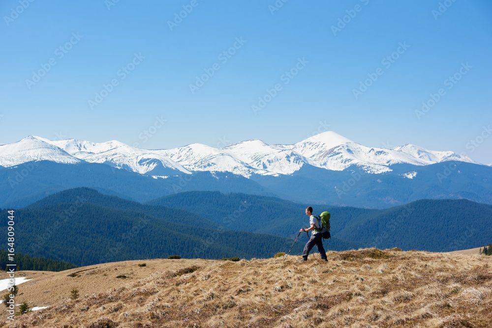 Male hiker with a backpack admiring the view walking on top of the mountain using hiking sticks copyspace achieving equipment athletic sportive lifestyle active Male hiker with a backpack admiring the view walking on top of the mountain using hiking sticks copyspace achieving equipment athletic sportive lifestyle active