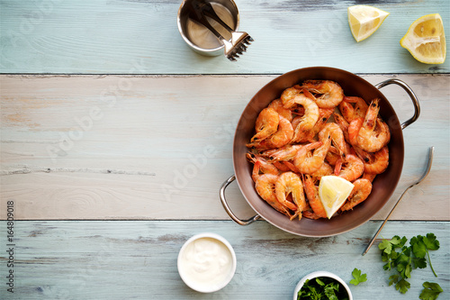 Fried prawns served with garlic sauce and parsley. Wooden "sea" background 

