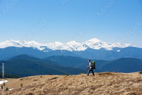 Male hiker with a backpack admiring the view walking on top of the mountain using hiking sticks copyspace achieving equipment athletic sportive lifestyle active