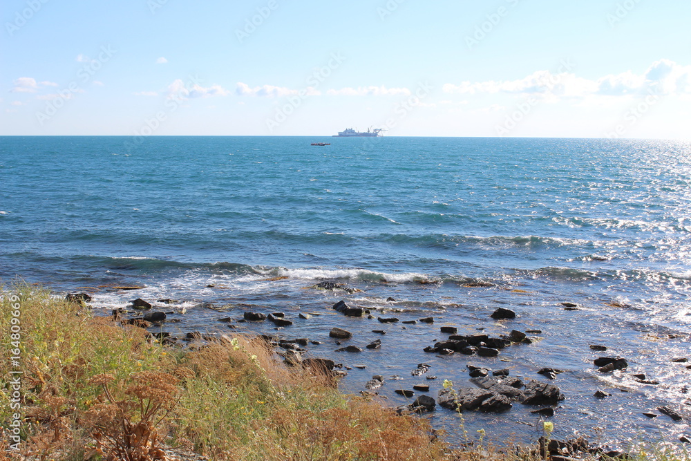 The Black Sea coast in a summer sunny day and the ship in the distance