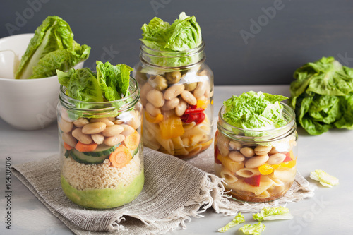 vegan couscous and pasta salad in mason jars with vegetables beans