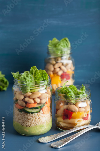 vegan couscous and pasta salad in mason jars with vegetables beans