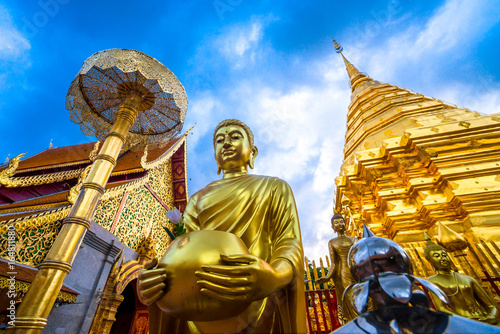 Golden buddha statue with golden pagoda background   At Wat Phra That Doi Suthep temple is tourist attraction of Chiang Mai  Thailand.Focus at face of buddha statue.