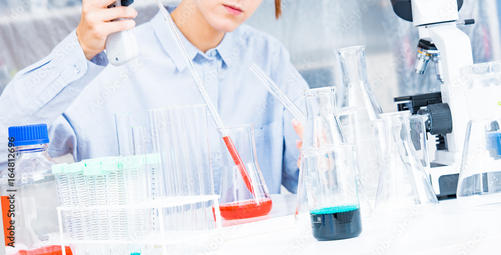 Fototapeta premium Woman Scientist Adding Liquid To Test Tube With Pipette In Lab