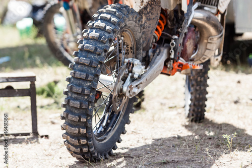 Fototapeta Naklejka Na Ścianę i Meble -  Close-up of muddy rear wheel and engine of dirt motorcycle