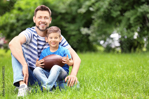 Dad and son with rugby ball in green park © Africa Studio