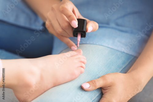 Young woman giving her little daughter pedicure at home, closeup