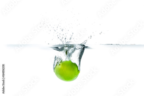 Fresh lime dropped into the water with water splash on a white background