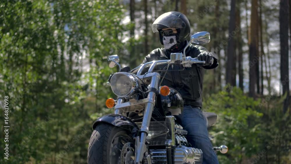 Confident biker sitting on his motorcycle in forest. Confident biker sitting on his motorcycle in forest.