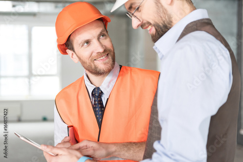Tableau sur toile Cheerful constructor speaking with beaming ganger