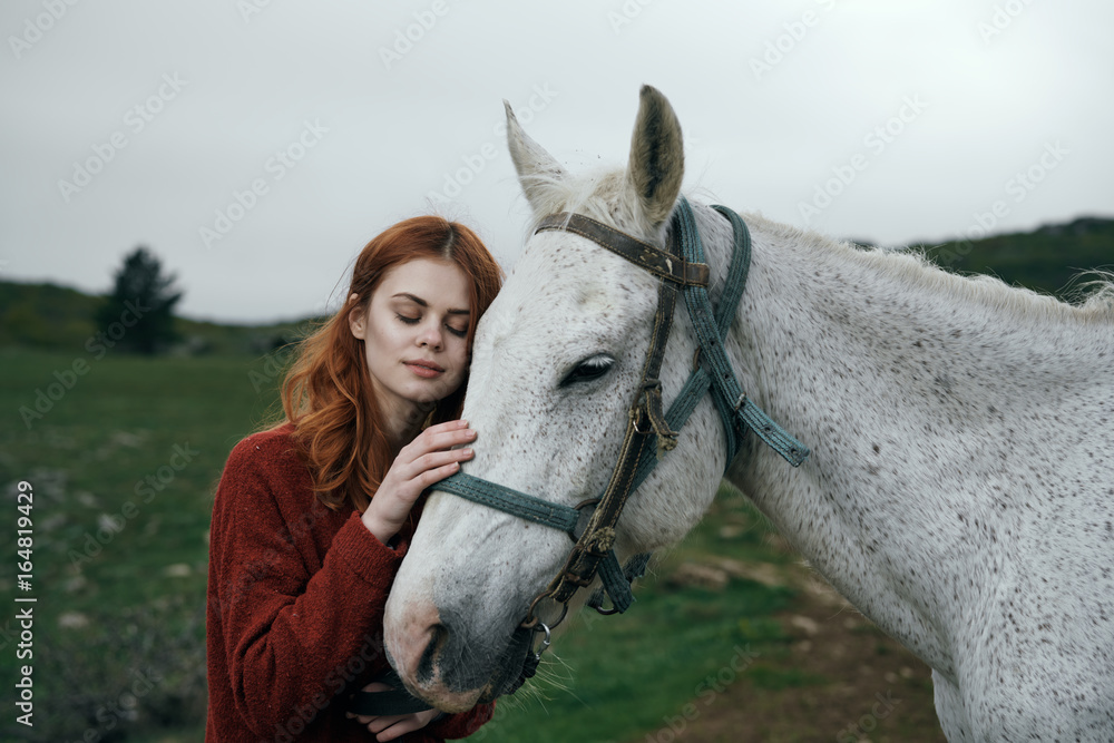 Fototapeta premium Young beautiful woman walking in the mountains with a horse