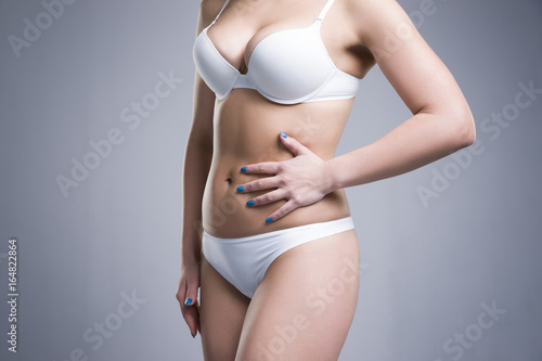 Woman in white underwear on gray background, cellulite on female body