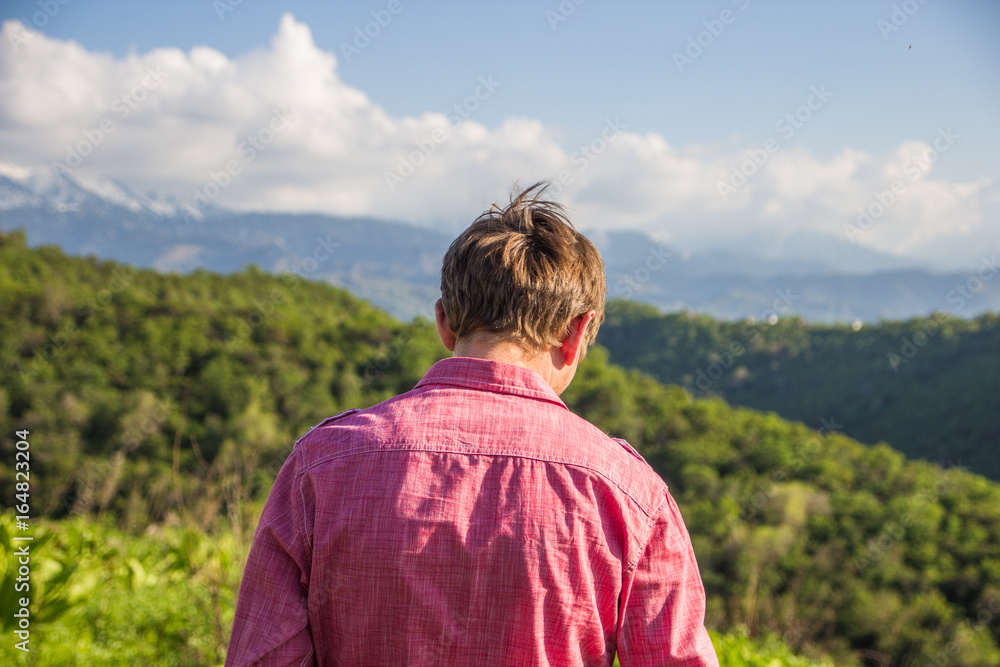 Young man in pink shirt from back enjoying beautiful mountain view