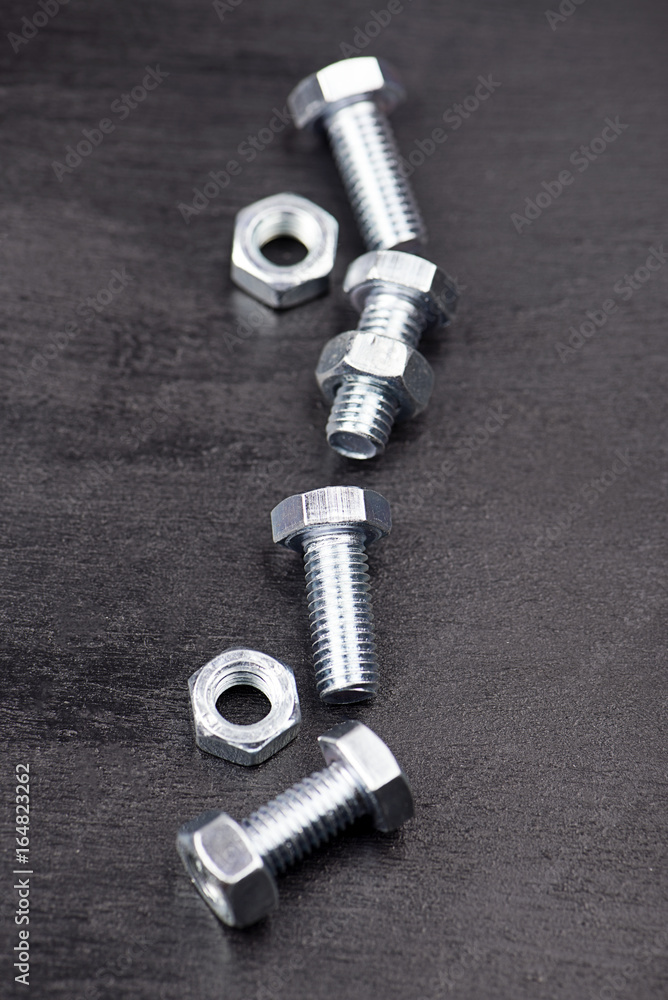 Background of nuts and bolts on black background. Vertical studio shot. Background of nuts and bolts on black background. Vertical studio shot.