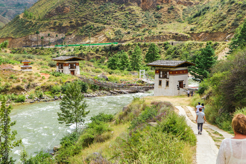 People walking towards the Iron Bridge of Tamchog Lhakhang Monastery, Paro River, Bhutan. 