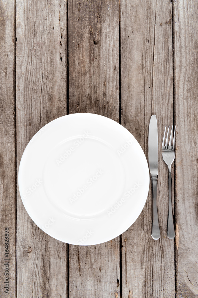top view of arranged empty plate, fork and knife on wooden table top view of arranged empty plate, fork and knife on wooden table