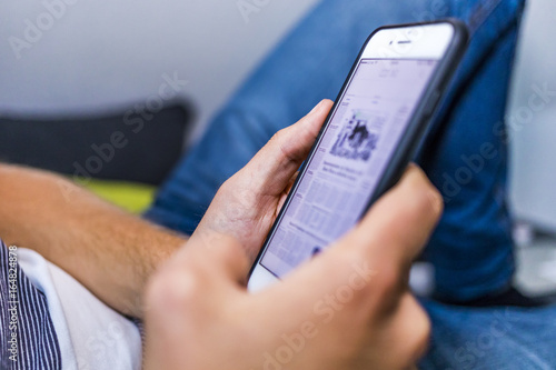 a man reading on his phone while lying on a couch