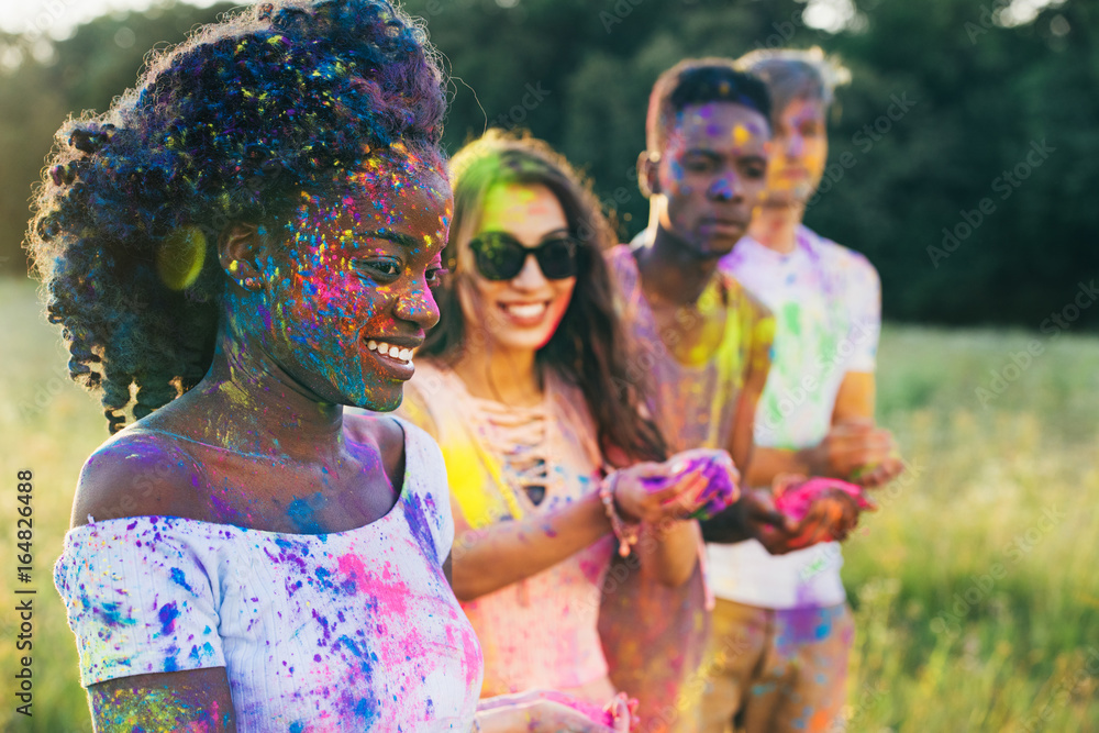 Φωτογραφία multicultural friends with colorful paint on clothing and bodies at holi festiva