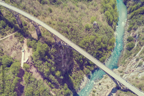 Top view of a car bridge across a river in the mountains. Toned