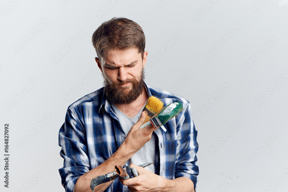 Young guy with a beard on a white isolated background holds tools for repair