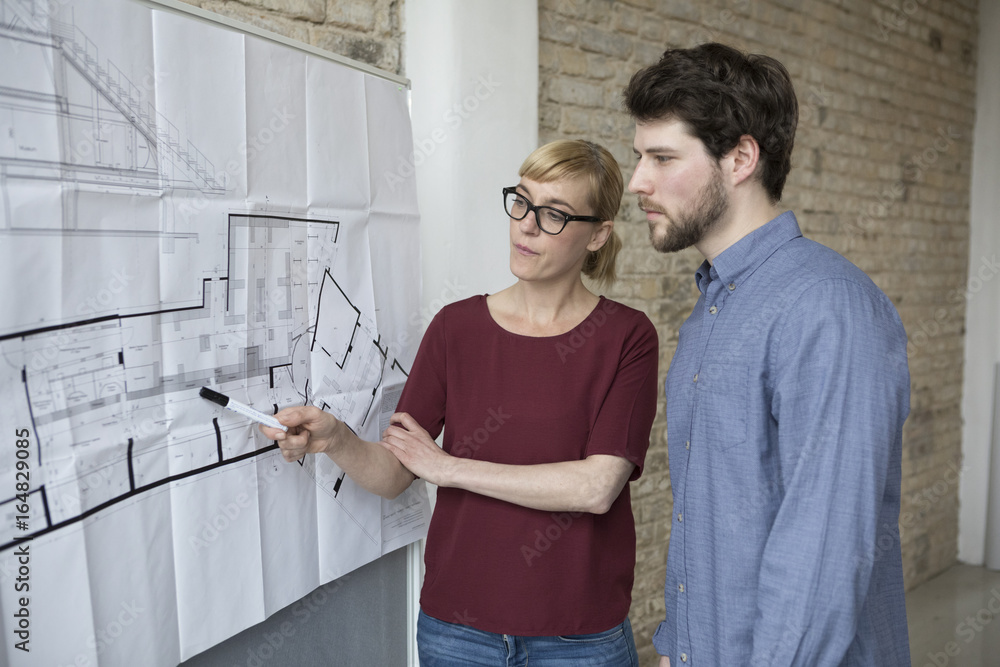 Businesswoman explaining new project to young colleague Businesswoman explaining new project to young colleague