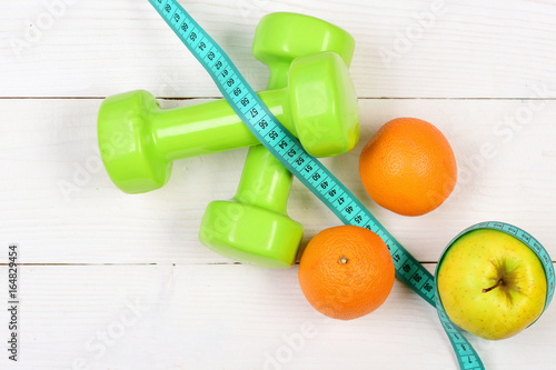 apple, orange with measuring tape, weight dumbbells for diet concept