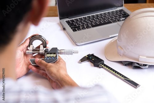 Engineer man hand measuring bearing with digimatic micrometer photo