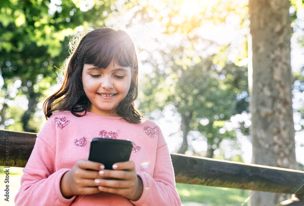 Smiling girl sending messages with her smartphone Smiling girl sending messages with her smartphone