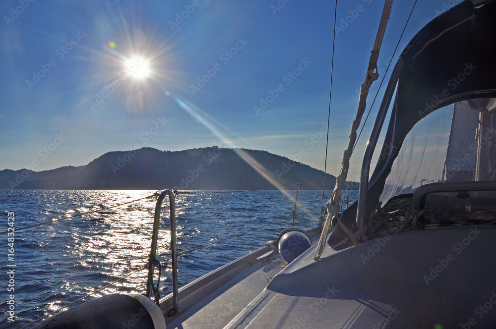 Fototapeta premium The view from the yacht to the island against sunlight