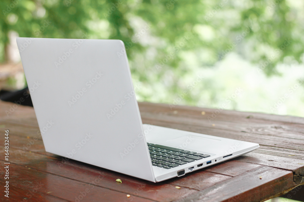 Stock photo :.Computer Laptop on wooden table with blur nature bokeh background, business technology concept