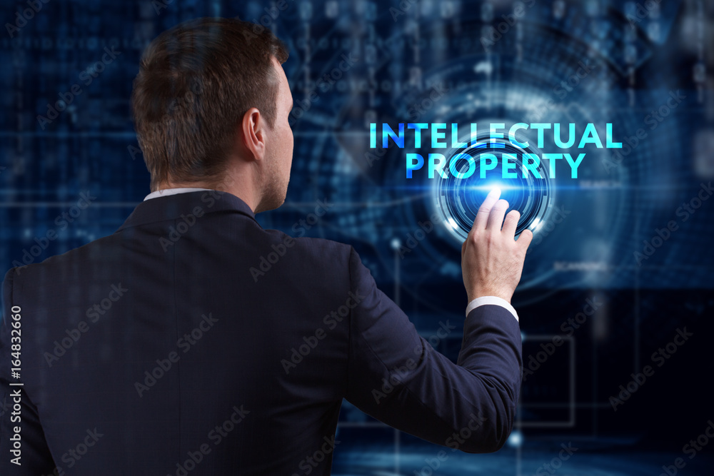 Business, Technology, Internet and network concept. Young businessman working on a virtual screen of the future and sees the inscription: Intellectual property Business, Technology, Internet and network concept. Young businessman working on a virtual screen of the future and sees the inscription: Intellectual property