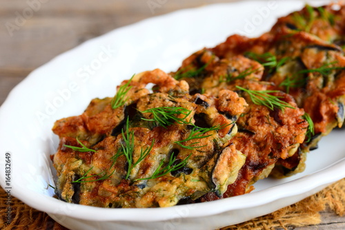 Fried eggplant cutlets. Crispy eggplant cutlets with garlic and dill on a white plate and a vintage wooden table. Easy vegetarian eggplant recipe. Closeup