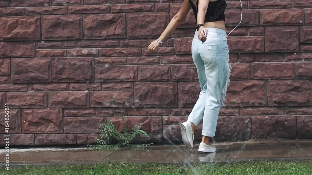 Girl hipster in ragged jeans crazy dancing and sings under water splashes. girl is having fun walking around the summer city. slow motion Girl hipster in ragged jeans crazy dancing and sings under water splashes. girl is having fun walking around the summer city. slow motion