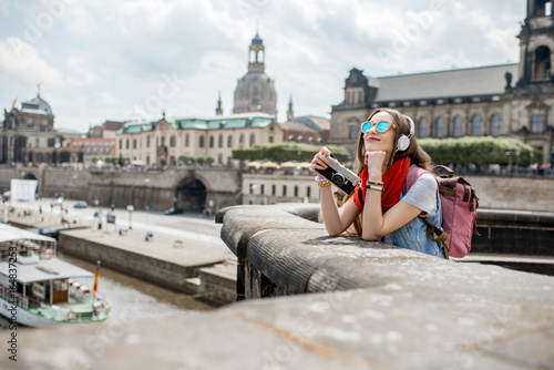 Young woman tourist with photo camera enjoying great view from the bridge on the old town of Dresden in Germany