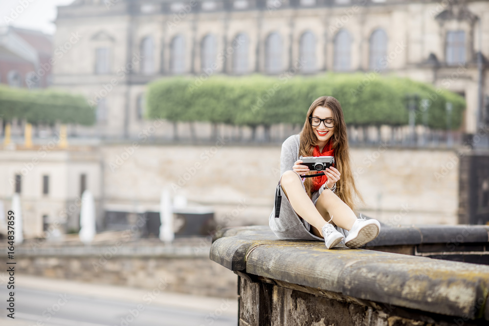 Young woman tourist with photo camera enjoying great view from the bridge on the old town of Dresden in Germany Young woman tourist with photo camera enjoying great view from the bridge on the old town of Dresden in Germany