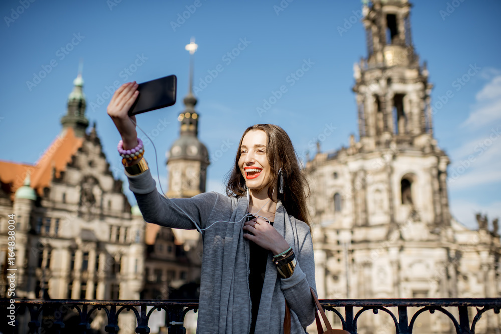 Young woman tourist making selfie photo with phone on the old town background in Dresden, Germany