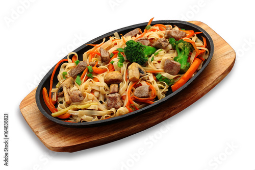 Udon noodles with meat vegetables and mashrooms on a stone plate isolated on white background