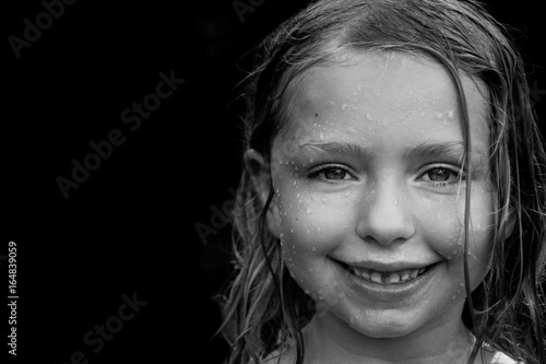 black and white of adorable child wet from playing outside in summertime