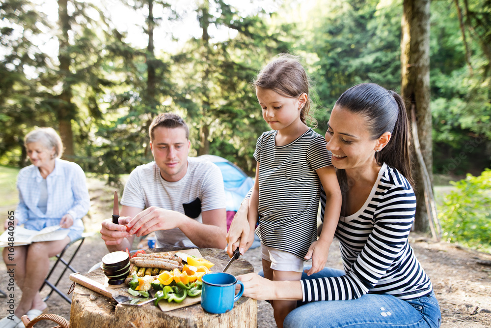 Beautiful family camping in forest, eating together.