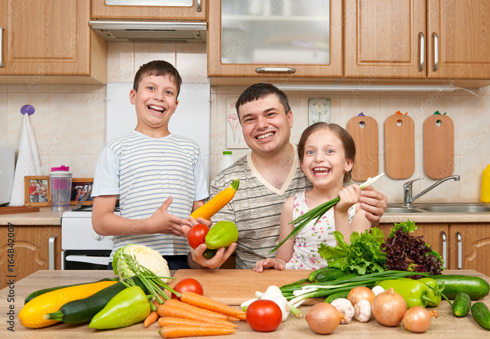 Father and two children in home kitchen interior. Happy family, girl and boy having fun with fruits and vegetables. Healthy food concept. Father and two children in home kitchen interior. Happy family, girl and boy having fun with fruits and vegetables. Healthy food concept.