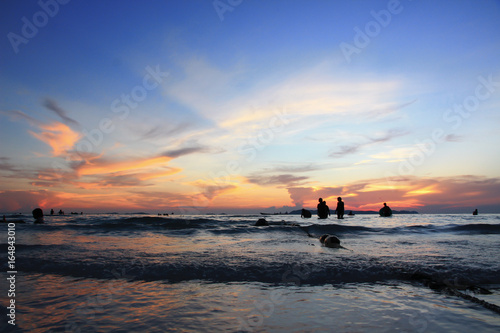 People in the sea, the sunset making two color blue and orange sky.
